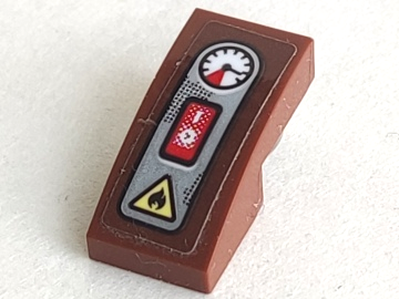 Brown LEGO curved slope 2x1x2/3 piece with a sticker of a control panel: a white gauge, a red switch, and a yellow fire symbol.