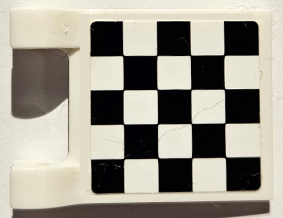 White LEGO 2x2 flag with a black and white checkered pattern on its square surface.