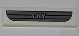 White LEGO 1x4 tile featuring a dark gray car grille with 'CITY' text sticker pattern.