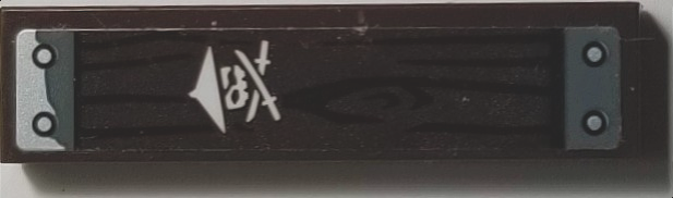 LEGO 1x4 dark wood grain tile with silver rivets and a white stylized ninja symbol featuring crossed swords.