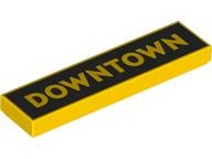 LEGO 1x4 yellow tile with 'DOWNTOWN' in gold on a black background pattern.