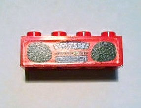 A red LEGO 2x4 brick with four studs on top, featuring a detailed radio boombox sticker pattern on its front.