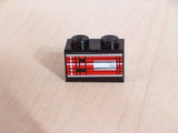 Black 1x2 LEGO brick with a sticker featuring a red, black, and white striped pattern resembling a vehicle's left taillight.