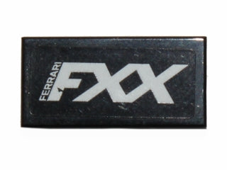 Close-up of a black LEGO 1x2 tile featuring a white 'FERRARI FXX' logo pattern, likely a sticker.