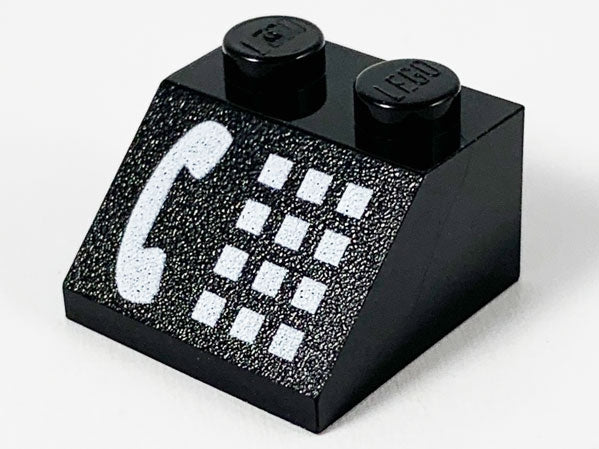 Black LEGO 45 2x2 slope brick with white phone receiver and button pattern print, two studs on top.