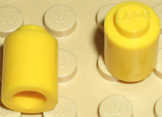 Two yellow LEGO 3062old round 1x1 bricks on a light baseplate. One shows the solid stud top, the other its hollow bottom.