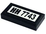 Black LEGO 1x2 tile, part 3069pb0108, with a white sticker featuring 'HH 7743' text, used in set 7743.