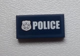 Dark blue LEGO 1x2 tile with white 'POLICE' text and a white star badge print.