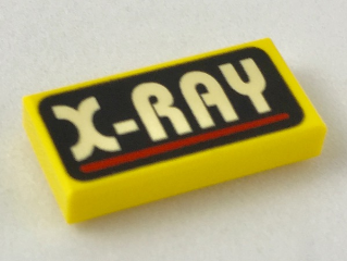A yellow LEGO 1x2 tile with 'X-RAY' in white text and a red line on a black background pattern.