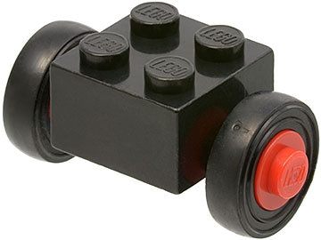 A black LEGO 2x2 modified brick with four studs, fitted with two red wheels and black tires, creating a small car chassis.