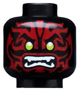 Black LEGO minifigure head with dark red alien face decorations, lime green eyes, and white fangs.