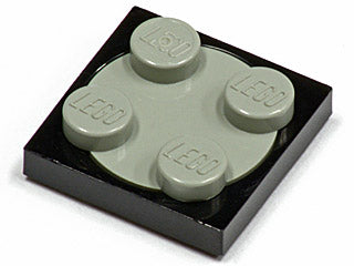 Close-up of a black LEGO 2x2 turntable plate with a light gray 2x2 rotating top piece that has four studs.