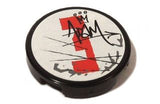 Round black LEGO 2x2 tile with white sticker, featuring a red number 3, gray splotches, black crown, and 'ADaM' graffiti.