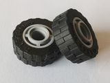 Two black LEGO tires with shallow staggered treads, mounted on grey 4-spoke wheel hubs.