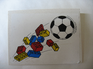 White LEGO slope sticker with a black and white soccer ball and scattered red, blue, and yellow LEGO bricks in motion.