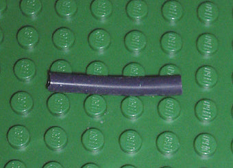 A dark gray LEGO 5102c04 pneumatic hose, 4mm diameter, 3.2cm long, on a green studded baseplate.