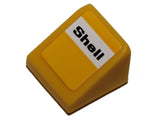 Yellow LEGO slope 30 1 x 1 x 2/3 brick with a white sticker featuring 'Shell' in black text.