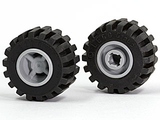 Two black LEGO tires with offset wide tread on light gray hubs. One wheel shows the outer hub, the other the notched pin hole.