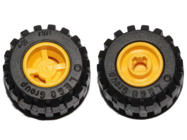 Two black LEGO wheels (87697) with yellow hubs, offset tread tires, and notched holes for wheel holder pins, against a white background.