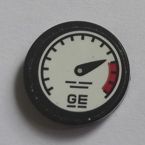 Round LEGO 2x2 tile with a gauge pattern, black needle pointing to red, and 'GE' letters. Features black rim and white face.