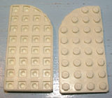 Two off-white LEGO 713old Plate, Round Curved 4 x 8 Right pieces. One shows the waffle bottom, the other the studded top.