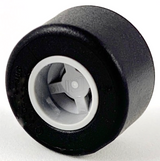 Black LEGO tire mounted on a light gray wheel hub with a notched center hole, viewed at an angle.