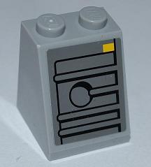 Light gray LEGO slope brick (2x2x2) with a black-lined pattern featuring ridges, a circle, and a small yellow rectangle.