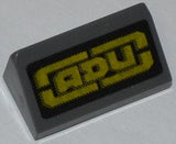 Dark grey LEGO slope brick 1x2x2/3 with a yellow 'ADU' logo on a black mesh background.