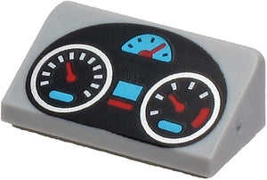 Light grey LEGO slope brick with a black oval dashboard pattern featuring silver, light blue, and red gauges.
