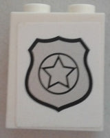 White LEGO 1x2x2 panel brick with side supports and hollow studs, featuring a silver police badge design with a star.
