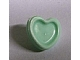 Close-up of a light green LEGO Friends heart hair decoration with a small pin, casting a slight shadow.