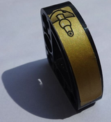 Black LEGO Technic 3x3 L-shape liftarm with gold sticker featuring a black coupling on a textured background.