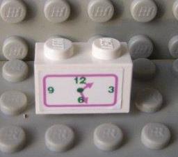 A white LEGO 1x2 brick with a dark pink and green clock pattern sticker showing numbers 3, 6, 9, 12 and hands at 6:15, on a gray studded surface.