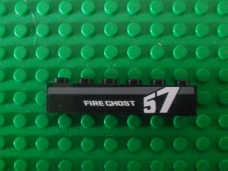 Close-up of a black LEGO 1x6 brick with a white and gray 'FIRE GHOST' and '57' pattern on a green baseplate.