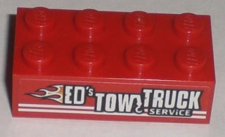 Red LEGO 2x4 brick with 'ED'S TOW TRUCK SERVICE' pattern and flame graphic on one side.