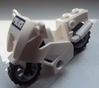 A white LEGO police motorcycle with 'POLICE' sticker on the front fairing, black wheels, and a light gray exhaust.