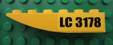 Yellow inverted curved 6x1 LEGO slope brick with 'LC 3178' sticker, on a green baseplate.