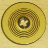 Close-up of a gold LEGO Technic Disk 3x3 with concentric black rings pattern and a central hole.