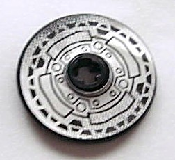 Close-up of a LEGO Technic Disk 3 x 3 with Disk Brake pattern in silver and black, featuring small bolts and geometric designs.