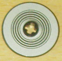 Close-up of a circular silver LEGO Technic 3x3 disk with concentric black rings and a gold cross-shaped pattern in the center.