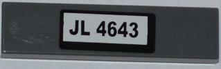 Dark grey LEGO 1x4 tile with a white sticker featuring 'JL 4643' in black text.