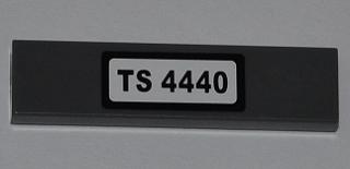 Dark grey LEGO 1x4 tile with a white sticker displaying 'TS 4440' in black text.