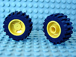 Two LEGO wheels, 18mm D. x 14mm with yellow hubs and black tires 30.4 x 14 (30285c01), on a blue baseplate.